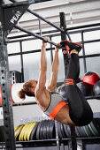 A young woman performing toes to bar windscreen wiper on a pull-up bar