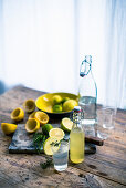 Homemade lemon and lime lemonade with ingredients on a rustic wooden table