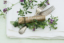 Cutlery and place markers made from pieces of hazel wood decorated with purple-flowering alfalfa (Medicago sativa)