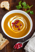 Cream of pumpkin soup with pomegranate seeds in a white bowl