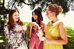 Three young women with tea cups in a garden