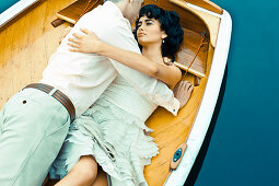 A dark-haired woman lying in a boat with a man