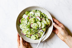 Creamy Cucumber Salad in a ceramic bowl on a marble work surface
