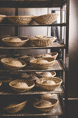Bread dough in proving baskets on a shelf in a bakery