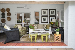 Sofa, armchairs and green Senufo stools on cosily furnished veranda