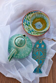 Ceramic teapot, dishes and fish ornaments glazed in shades of turquoise