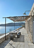 Terrasse mit Natursteinboden und Blick aufs Meer bei blauem Himmel