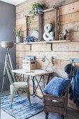 Desk against wooden wall and denim cushions in wooden crate on castors
