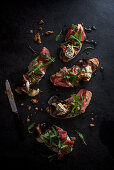 Sourdough bread slices topped with roasted figs with blue cheese, walnuts, ham, rocket and olive oil