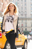 Junge blonde Frau in T-Shirt, Bikerjacke und schwarzer Hose