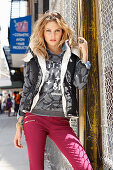 Junge blonde Frau in Shirt, Jacke und dunkelroter Hose