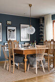 Wooden tables and chairs with fur blankets in dining room with blue walls