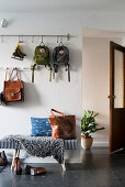 Metal rod with hooks and coat pegs in hallway with dark tiled floor