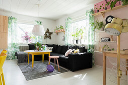 Black sofa in sunny living room with colourful accents