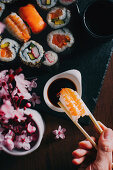 Hand taucht Nigiri-Sushi mit Essstäbchen in Sojasauce (Japan)