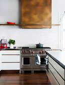 Extractor hood above stove in kitchen with white wall tiles