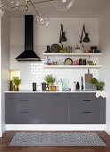 Grey kitchen counter, extractor hood, white wall tiles and shelves