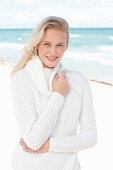 Junge blonde Frau in weißem Pullover am Meer