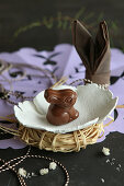 Chocolate Easter bunny in small hand-made ceramic dish on raffia nest