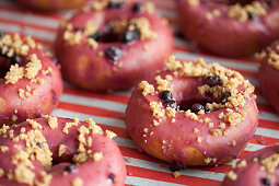 Donuts mit rosa Zuckerglasur, Streuseln und Heidelbeeren