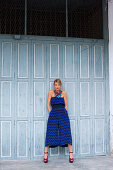 Junge Frau in blauem 7/8-Overall und roten High Heels