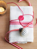 Cloth napkin wrapped and decorated with gift ribbon and bauble