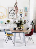 Esstisch mit bunten Stühlen, darüber Pendelleuchte mit Korb, moderne Kunst an der Wand