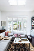 Corner sofa and coffee table with marble top in the living room, patio door in the background