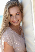 A young blonde woman on a beach wearing a beige polka-dot dress