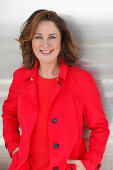 A brunette woman wearing a red top and a red trench coat