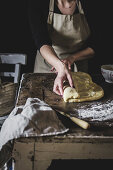 Woman rolling dough for sweet pastry on kitchen table