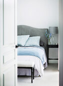 Glance into the bedroom on a double bed with a gray headboard and a clothes bench