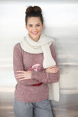 Brünette Frau mit weißem Schal in rosa-grau meliertem Strickpullover