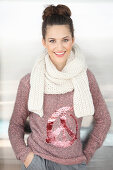 A brunette woman wearing a white scarf with a mottled pink-grey knitted jumper