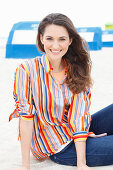 A brunette woman wearing a striped blouse and jeans