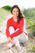 Brunette woman wearing red knit sweater and white trousers