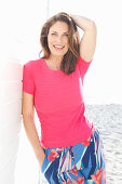 Brunette woman wearing pink T-shirt and multicoloured trousers on beach