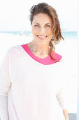 Brunette woman wearing pink T-shirt and white sweater on beach