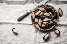 Frozen mussels in metallic vintage plate on linen tablecloth with stripes