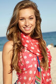 A young blonde woman by the sea wearing a beach towel