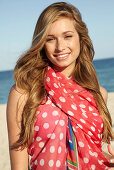 A young blonde woman by the sea wearing a beach towel