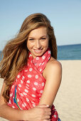 A young blonde woman by the sea wearing a beach towel