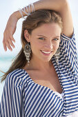 A young brunette woman on a beach wearing a black-and-white striped top