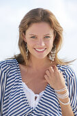 A young brunette woman on a beach wearing a black-and-white striped top