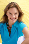 A young brunette woman wearing a blue shirt in front of a yellow parasol