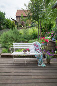 Weiße Bank mit Kirschen, Kissen und Häkeldecke auf Terrasse