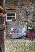 Cushions and crocheted blanket on white bench on terrace