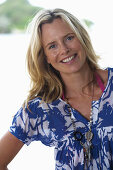 A young blonde woman on a beach wearing a blue-and-white patterned shirt