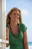 Junge blonde Frau im grünen Shirt am Strand
