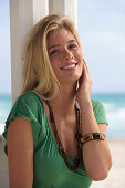A young blonde woman on a beach wearing a green top